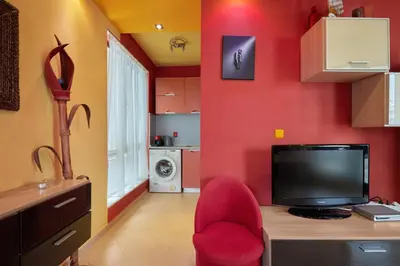 a room with a desk with a television and a red wall at The Love Nest - 1BD Apartment in Sunny Beach by Flat Mаnаger in Sunny Beach