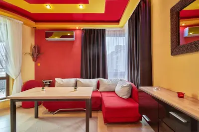 a living room with a red couch and a table at The Love Nest - 1BD Apartment in Sunny Beach by Flat Mаnаger in Sunny Beach