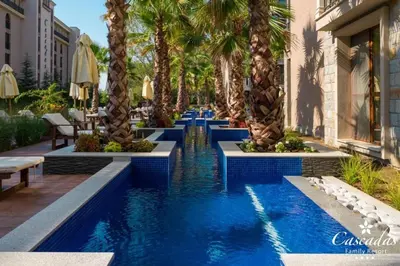 a resort pool with palm trees and chairs at Apartament CASCADAS FAMILY in Sunny Beach