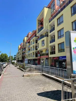 a city street with buildings and a sidewalk with cars at VV Vigo Apartments in Nesebar