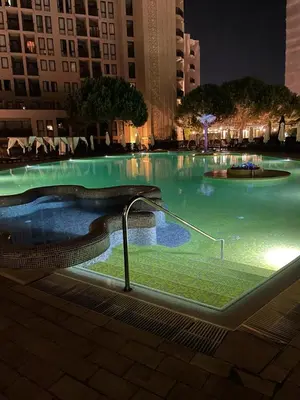 a large swimming pool with green water at night at Royal Beach NICE VIEW in Sunny Beach