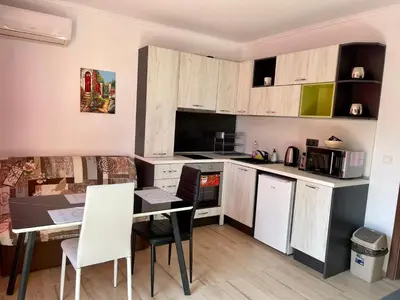 a kitchen with wooden cabinets and a table and a dining room at A Tiny Flat in Sunny Beach