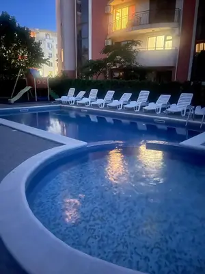 a swimming pool with white lounge chairs and a hotel at A Tiny Flat in Sunny Beach