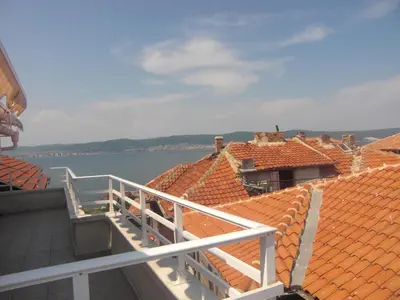 a balcony with orange tiled roofs and the water at Guest House Antoaneta in Nesebar