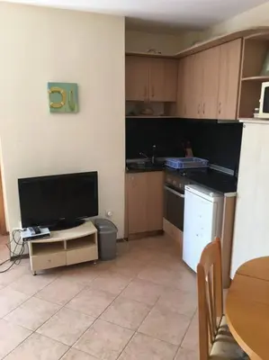 a kitchen with a tv and a table and a kitchen with a counter at 3 Bedroom Apt with Pool Views at Arcadia Complex in Sunny Beach