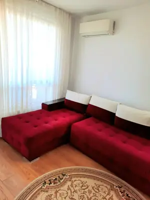 a red couch in a living room with a window at Прекрасный апартамент с видом на море и бассейном in Byala