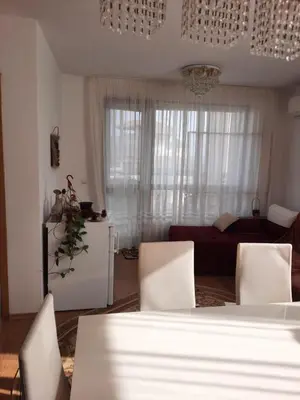 a living room with a table and chairs and a couch at Прекрасный апартамент с видом на море и бассейном in Byala