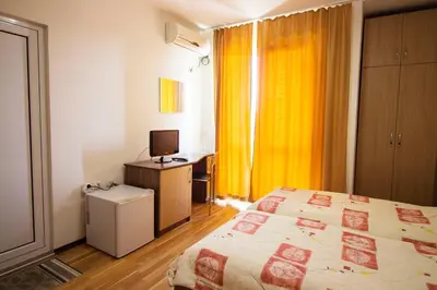 a bedroom with a bed and a desk with a television at Ivatea Family Hotel in Ravda