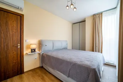 a bedroom with a bed and a wooden door at Brand New Downtown Apartment in Varna City