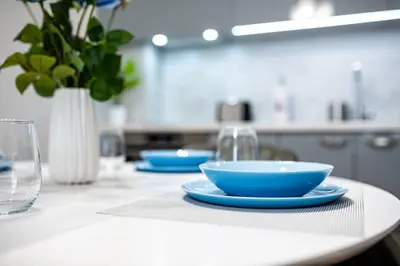 a white table with blue bowls and glasses on it at Brand New Downtown Apartment in Varna City