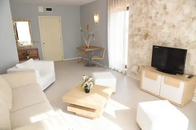 a living room with white furniture and a flat screen tv at Hotel Paradise Garden in Chernomorets