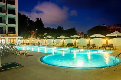 a pool with chairs and umbrellas at night at Cantilena Complex in Sunny Beach