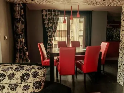a dining room with a table and red chairs at Aпартамент в близост до морето и центъра in Burgas City