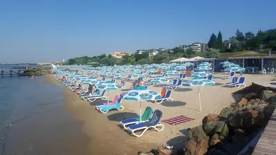 a bunch of lawn chairs and chairs on a beach at Комплекс Конти in Ravda