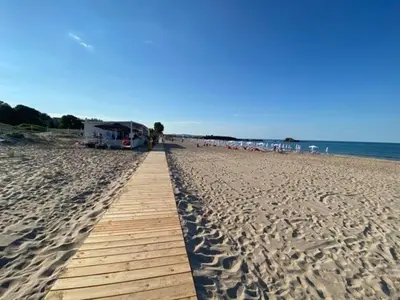 a boardwalk on a beach with a group of people at Студио Симона 5 първа линия море in Lozenets
