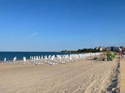 a beach with chairs and umbrellas and the ocean at Студио Симона 5 първа линия море in Lozenets
