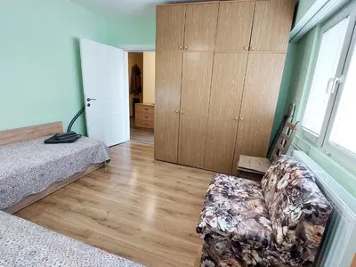 a bedroom with a bed and a couch and a window at Апартамент за гости , жк. Зорница, бл.36 in Burgas City
