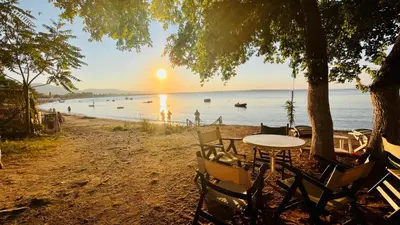 a table and chairs on a beach with the sunset at Cozy Home Santa Marina Sozopol in Sozopol