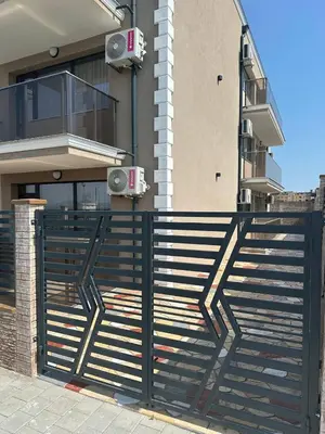 a black fence in front of a building with speakers at Studios and Apartments Pomorie in Pomorie