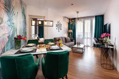 a living room with a table and green chairs at Stylish Sea View Apartment 3 Min to Beach Balcony & Comfort in Pomorie