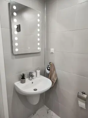 a white bathroom with a sink and a mirror at Sea apartment Lazur - next to the beach in Burgas City