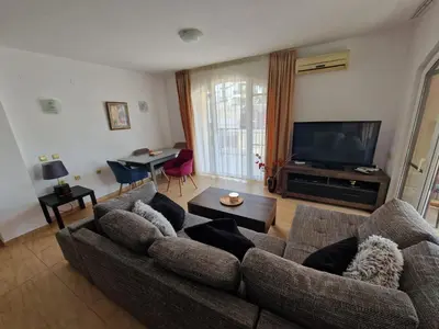 a living room with a couch and a flat screen tv at Aqua Dreams A4, Sveti Vlas , A much sought after complex. in Burgas City