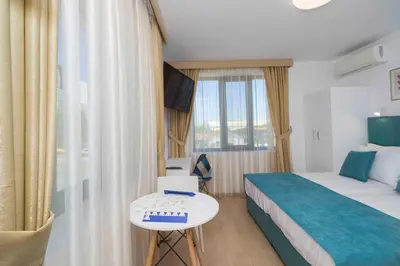 a hotel room with a bed and a table and a window at Електра Апарт Бургас Electra Apart Burgas Elektra Bourgas in Burgas City
