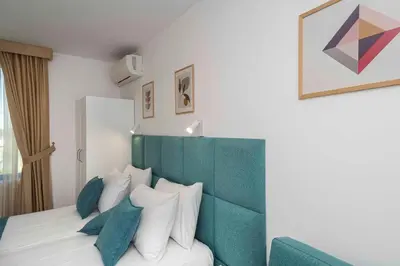 a bedroom with a bed with a green headboard and pillows at Електра Апарт Бургас Electra Apart Burgas Elektra Bourgas in Burgas City
