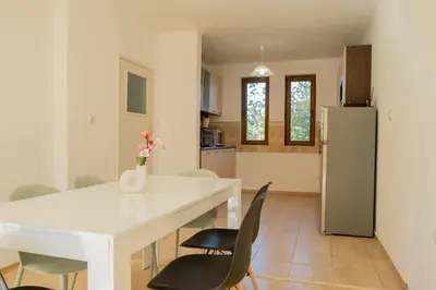 a kitchen and dining room with a white table and chairs at Indigo Villas in Pismenovo