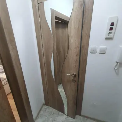 a bathroom with a wooden door with a mirror at Apartment Voivoda in Varna City