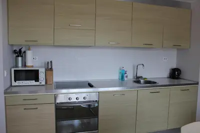 a kitchen with wooden cabinets and a sink and a microwave at Private Apartments in Yoo Bulgaria Complex in Obzor