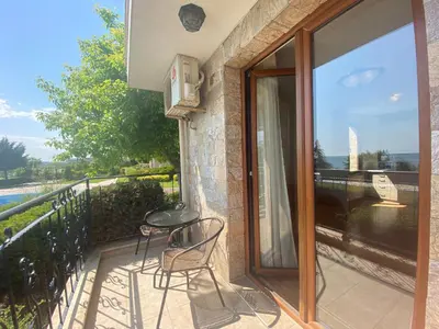 a balcony with two chairs and a glass door at ROYAL BAY 6 Sea View Apartment in Sveti Vlas