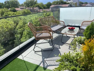 three chairs and a table on a balcony with a view at Panoramic apartment in Varna with underground parking in Varna City