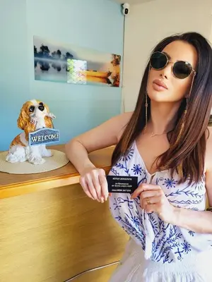 a woman in sunglasses holding a card next to a dog at Хотел ЗОНАРИТА in Primorsko