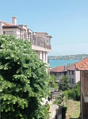 a view of a building with a tree in the foreground at Apartament Lili Sozopol in Sozopol