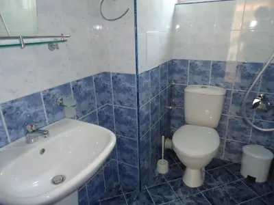 a blue and white bathroom with a toilet and a sink at Pension RUSKOVI GuestHouse in Ravda