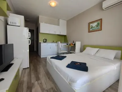 a bedroom with a large white bed and a kitchen at Studio Sorrento Sole Mare-Bastet BS in Sveti Vlas