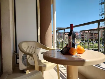 a table with a bottle of wine and oranges on a balcony at Studio Sorrento Sole Mare-Bastet BS in Sveti Vlas