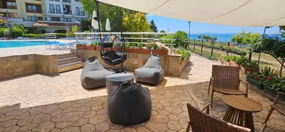 a patio with chairs and an umbrella and a pool at Apartament Sorrento in Marina Cape in Aheloy