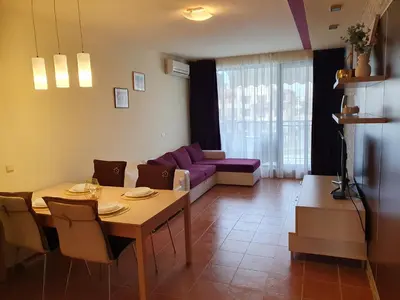 a living room with a table and a purple couch at Sea Star Sozopol in Sozopol