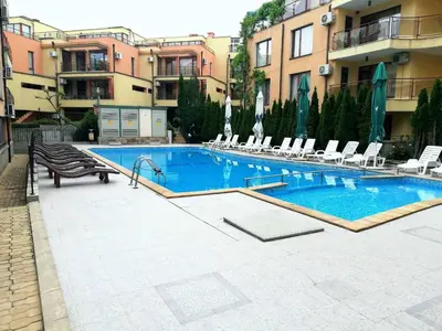 a large swimming pool with chairs and a building at Sveti Vlas Modern Studio with Pool & Balcony by Flat Mаnаger in Sveti Vlas