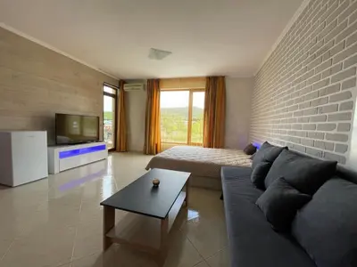 a living room with a couch and a television at Sveti Vlas Modern Studio with Pool & Balcony by Flat Mаnаger in Sveti Vlas