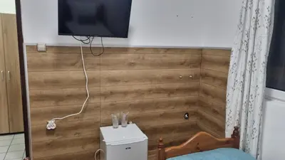 a bedroom with a wooden wall with a tv on it at Къща за гости Пиргос in Burgas City