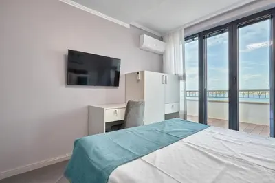 a bedroom with a bed and a television and a balcony at 3BD Beach Paradise with a Stunning View with Parking by Flat Mаnаger in Nesebar