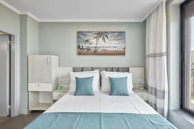 a bedroom with a large white bed with blue pillows at 3BD Beach Paradise with a Stunning View with Parking by Flat Mаnаger in Nesebar