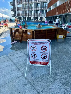 a sign in front of a swimming pool with two dogs at Sea View Private Studio Paradiso B 509 in Nesebar