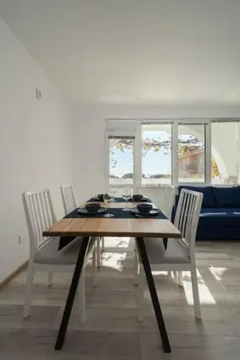 a dining room table with four chairs and a blue couch at Boutique Blue Apartment in Sveti Vlas