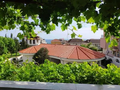 a building with a red roof and some bushes at Boutique Blue Apartment in Sveti Vlas
