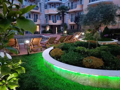 a garden with chairs and lights in front of a building at MARINA Apartments in Ravda