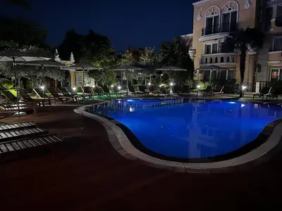 a large swimming pool with blue water at night at MARINA Apartments in Ravda